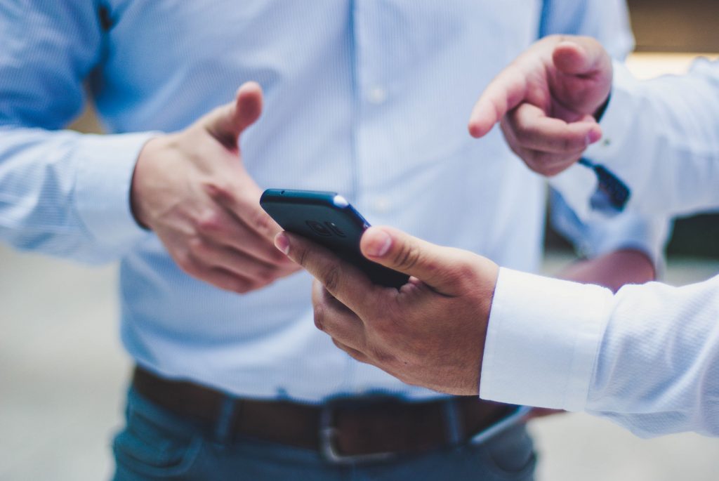 One man assisting another with mobile device